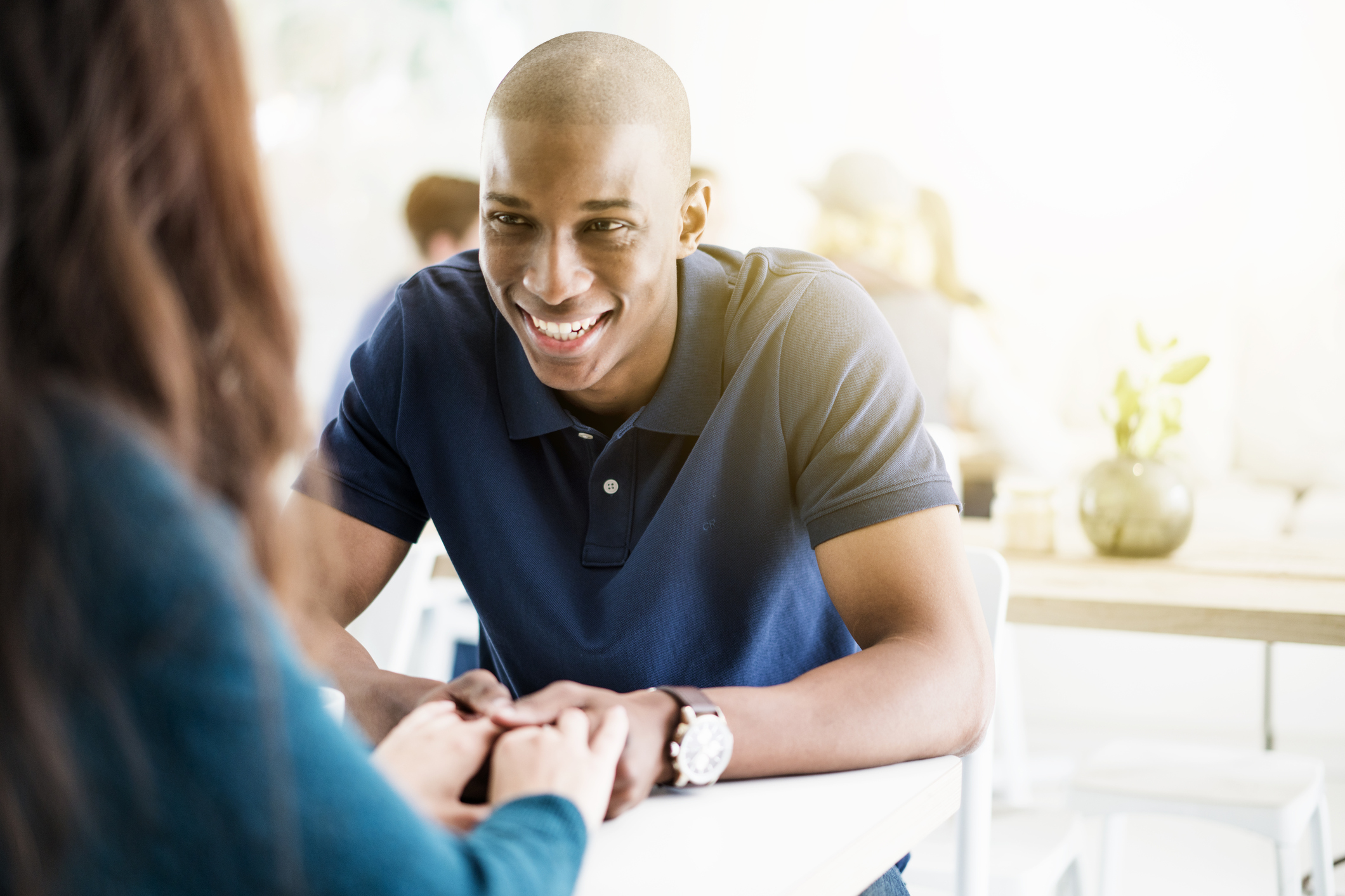 Smiling young man holding hands of woman in cafe